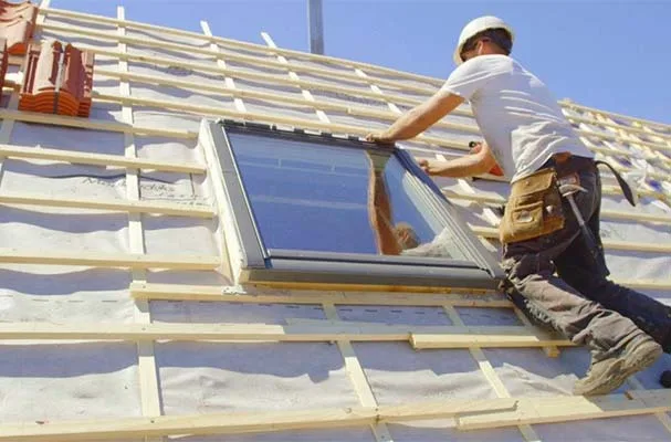 Installer fitting a roof window on a pitched roof