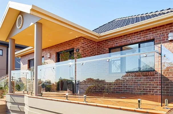 Frameless glass balustrade fixed with stainless standoffs on a brick house terrace