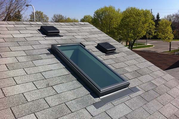 Newly replaced flat skylight installed on a shingle roof