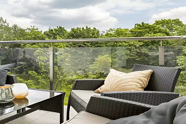 Stainless steel post-and-rail glass balustrade around a balcony overlooking trees