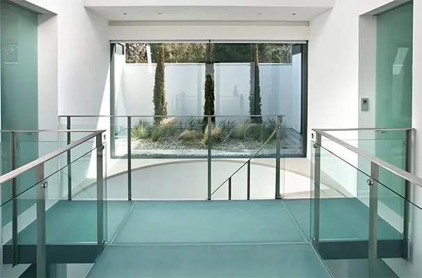 Indoor frameless glass balustrade with a stainless steel handrail on a bright internal landing