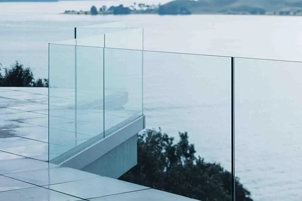 Tall frameless glass balustrade panels in a slim base channel overlooking water