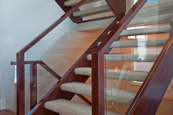 Timber posts and handrail with glass infill panels on a carpeted staircase