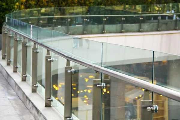 Curved glass balustrade with posts and a handrail on an outdoor walkway