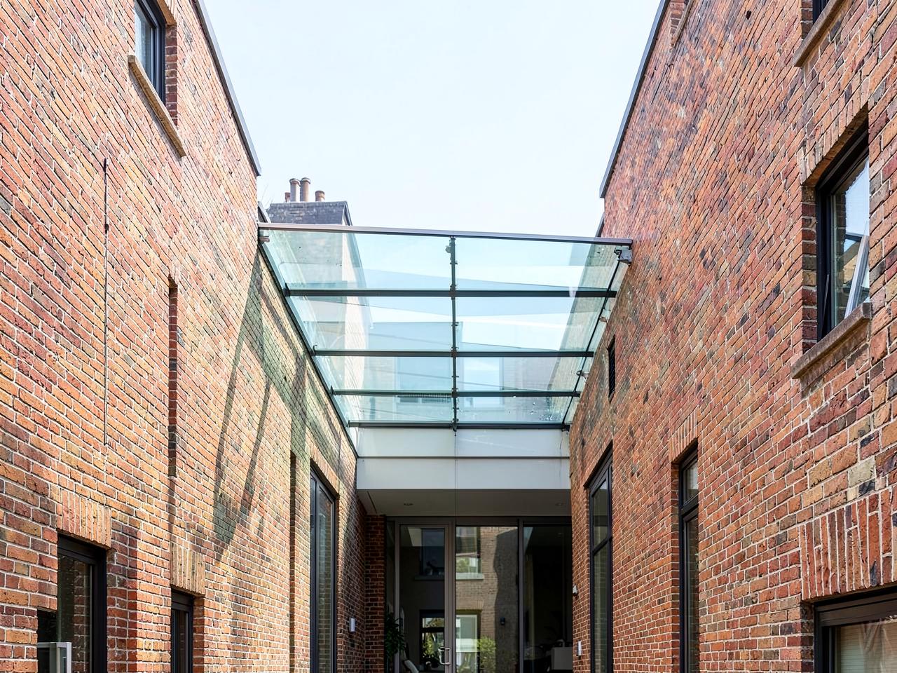 Frameless structural glass roof linking two buildings